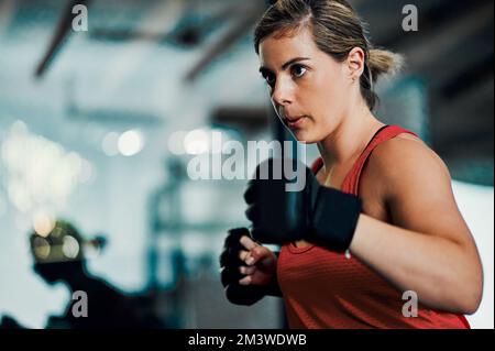 Dynamit ist in kleinen Packungen erhältlich. Eine attraktive junge Kickboxerin, die im Fitnessstudio trainiert. Stockfoto