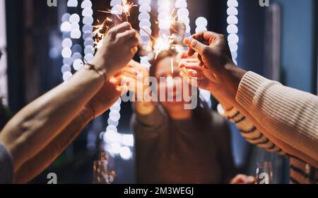 Weihnachten kommt. Eine Gruppe junger Freunde, die mit Sparklern auf einer Weihnachtsfeier spielen. Stockfoto