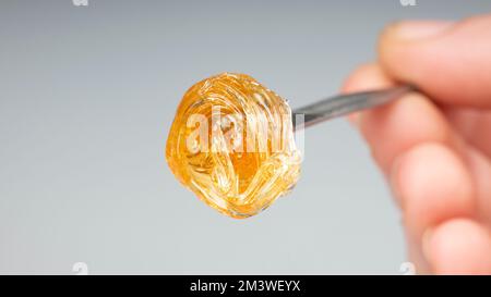 Gelber Harzextrakt auf Tupfer-Werkzeug-Nahaufnahme, Goldwachsabstrich für Kifferrauch. Stockfoto