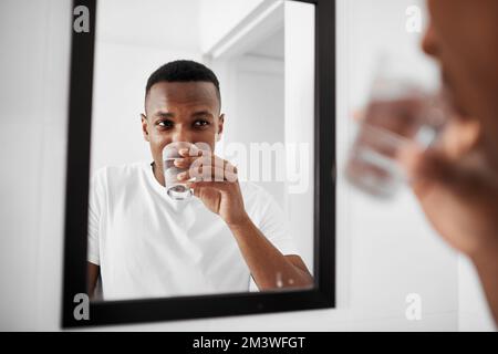 Eine gute Spülung genügt. Ein junger Mann, der sich zu Hause im Bad mit Wasser den Mund ausspült. Stockfoto