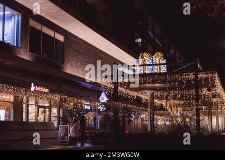 Hasselt. Limburg-Belgien 12-12-2021. Stadt bei Nacht in Weihnachtsbeleuchtung. Die Leute schauen auf die dekorierten Schaufenster. Belchiсken Café Stockfoto