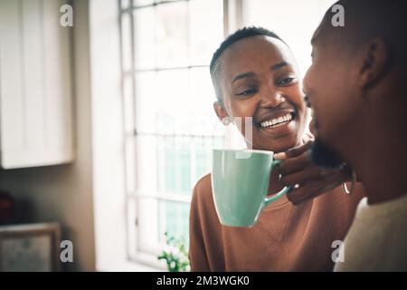Kaffee und Unterhaltung, um den Tag zu beginnen. Eine wunderschöne junge Frau, die Kaffee trinkt und sich mit ihrem Mann zu Hause unterhält. Stockfoto