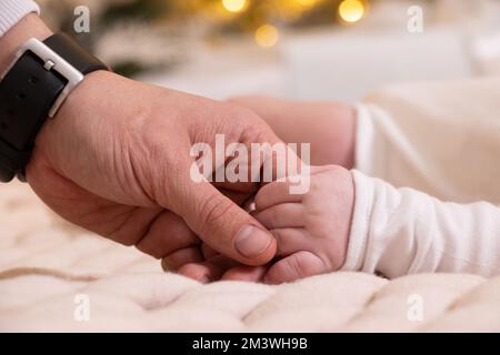 Dads Hand hält die Hand eines Neugeborenen Nahaufnahme, Liebe und Familie, die Hand eines Neugeborenen, Kinder Stockfoto