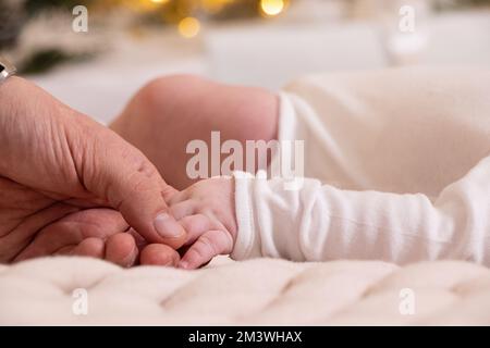 Dads Hand hält die Hand eines Neugeborenen Nahaufnahme, Liebe und Familie, die Hand eines Neugeborenen, Kinder Stockfoto