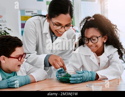 Wissenschaft ist unsere Art von Magie. Zwei niedliche Schüler experimentieren und schleimen mit ihrem Naturwissenschaftslehrer. Stockfoto