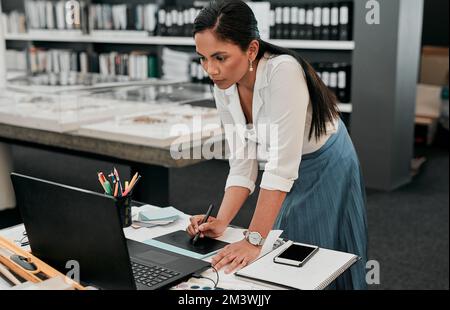 Diese virtuelle Kopie meines Plans wird meinem Verkaufsgespräch wirklich helfen. Eine junge Designerin, die an ihrem Laptop arbeitet. Stockfoto