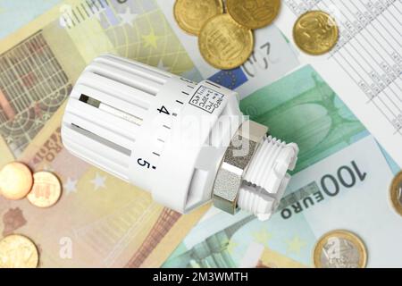 Thermostatischer Ventilkopf auf Euro-Banknoten-Hintergrund. Steigender Verbrauch. Konzept der Stromkosten und teurer Energie. Preiserhöhung. Heizung Cr Stockfoto