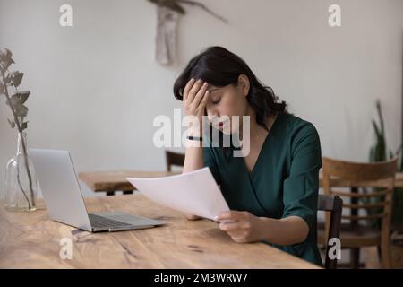 Aufgebrachte, erschöpfte, freiberufliche Mitarbeiterin, die fälschlicherweise eine Stellenanzeige bekommt Stockfoto