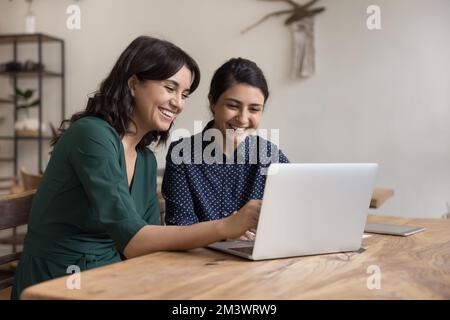 Zwei fröhliche, vielfältige Büroangestellte, die an einem Projekt mitarbeiten Stockfoto