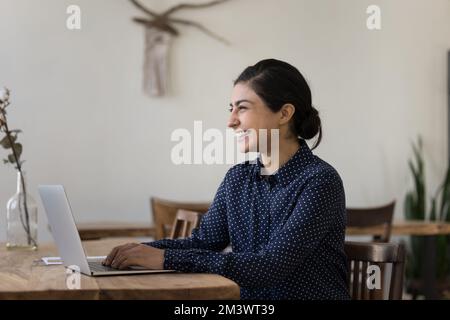 Fröhliche Freiberuflerin der Generation Y, indische Geschäftsfrau, die mit einem Notebook arbeitet Stockfoto