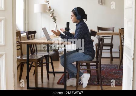 Professionelle indische Radio-Moderatorin mit Kopfhörern, die auf Sendung spricht Stockfoto