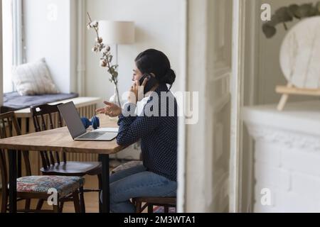 Eine fleißige, junge indische Freiberuflerin, die mit dem Handy telefoniert Stockfoto