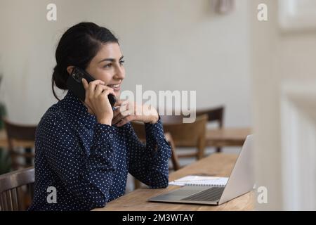 Glückliche beschäftigte, hübsche indische Geschäftsfrau, die mit dem Handy telefoniert Stockfoto