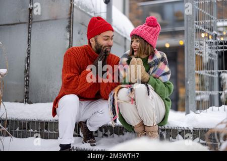 Ein junges Paar sitzt im Winter auf der Veranda ihres Hauses Stockfoto