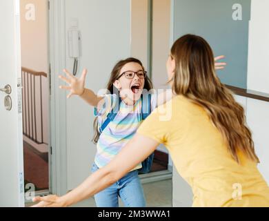 Kind Mutter Tochter Rucksack Haus Bildung Schule Familie Student willkommen Umarmung zusammen liebe Frau elementare Hause Mädchen Frau Stockfoto