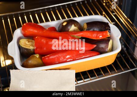 Rote Paprika und Auberginenbraten auf dem Ofen zur Vorbereitung der Zubereitung von Ajvar, einem traditionellen serbischen Gericht. Selektiver Fokus Stockfoto