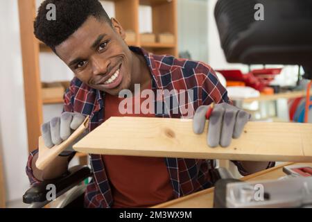 Junger Mann im Rollstuhl versucht sich selbst, sein Bücherregal zu falten Stockfoto