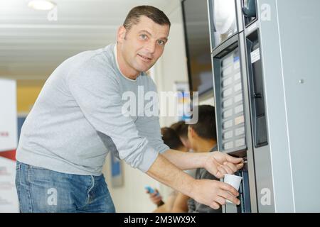 Porträt eines Mannes, der Getränke aus dem Automaten bekommt Stockfoto