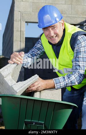 Porträt eines Arbeiters mit Ziegeln in der Schubkarre Stockfoto