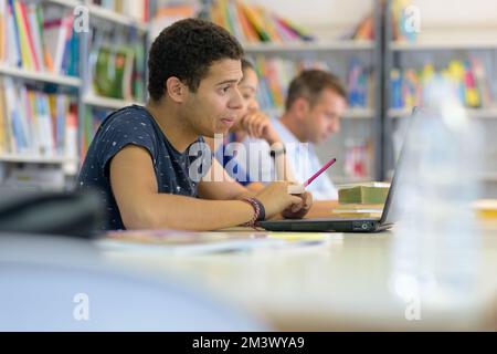 ein College-Student studieren in der Bibliothek mit laptop Stockfoto