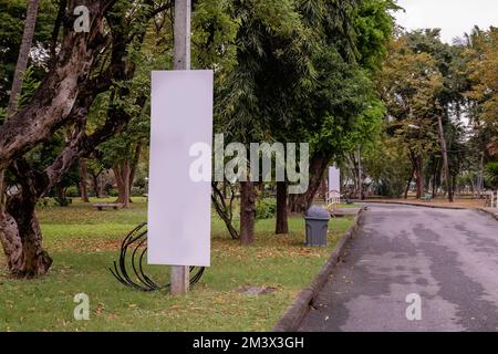 Leeres weißes Schild neben einer Straße in einem Park Stockfoto