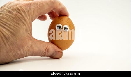 Männlicher Koch mit einem Hühnerei, dessen Augen auf weißem Hintergrund isoliert sind Stockfoto