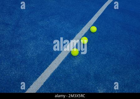Drei Paddle-Tennisbälle auf einem blauen Kunstrasen nahe der Mittellinie Stockfoto