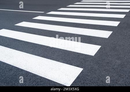 Frisch bemalte Fußgängerbrücke. Asphalt auf der Straße markiert. Neuer Fußgängerzebrahintergrund in der Stadtstraße Stockfoto