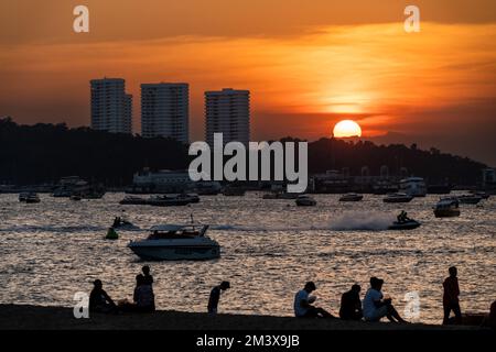 Menschen hängen bei Sonnenuntergang am Pattaya Beach ab. Das tägliche Leben in Pattaya, Provinz Chonburi, Thailand am 17. Dezember 2022. Das bei Touristen sehr bekannte Gebiet ist einer der Schwerpunktbereiche, die die thailändische Tourismusbehörde (Tat) gefördert hat, um mehr ausländische Touristen in das Land zu locken und damit seine tourismusabhängige Wirtschaft zu retten. Stockfoto