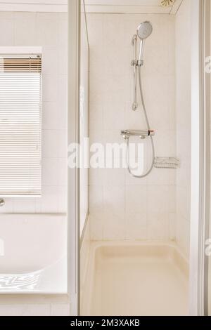 Badezimmer mit Badewanne, Duschkopf und Handläufen an der Wand vor der Badewanne Stockfoto