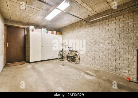 Ein Zimmer mit einem Fahrrad in der Ecke und einer offenen Tür, die zu einem anderen Zimmer führt, das weiß gestrichen wurde Stockfoto