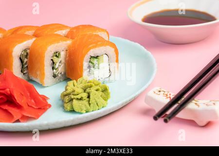 Japanisches Speisekonzept. Sushi-Brötchen Philadelphia mit Lachs und Frischkäse auf einem Teller mit Ingwer und Wasabi. Sushi-Menü. Traditionelle japanische Küche Stockfoto