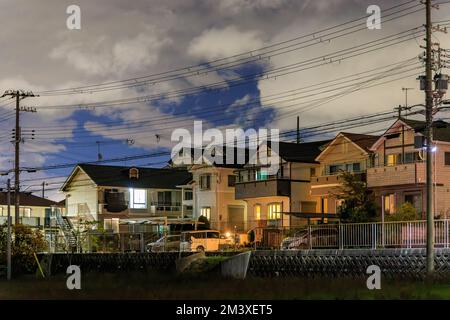 Zweistöckige Vorstadthäuser in einer ruhigen Straße unter Wolken in der Nacht Stockfoto