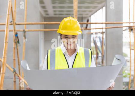 Eine Frau mit einem Grundriss, der aussieht, Bauplan, fröhliches Lächeln Stockfoto
