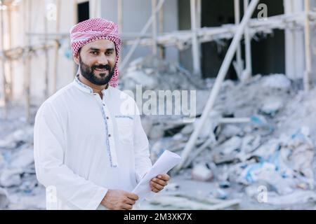 arabisch-muslimischer Erwachsener-Ingenieur-Business männliches Porträt mit Grundriss auf der Baustelle Stockfoto