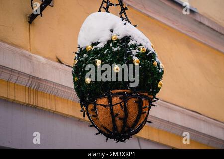 Weihnachten in Vilnius. Das Gebäude ist mit schneebedeckten Weihnachtskompositionen dekoriert, mit grünen Tannenbäumen, beleuchteter Girlande und goldenen Weihnachten Stockfoto
