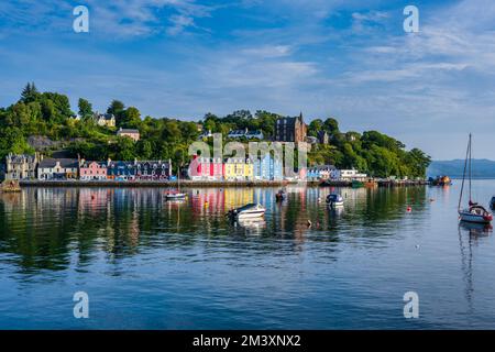 Boote ankern im Hafen von Tobermory mit farbenfrohen Reflexionen der Häuser am Ufer - Tobermory, Isle of Mull, Schottland, Großbritannien Stockfoto