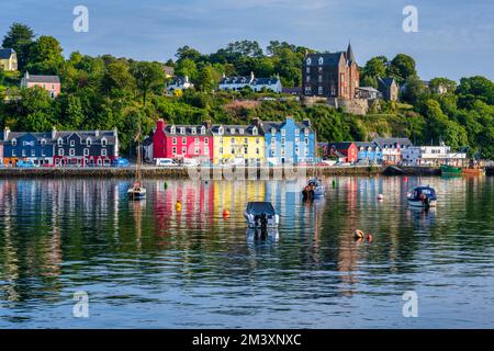 Boote ankern im Hafen von Tobermory mit farbenfrohen Reflexionen der Häuser am Ufer - Tobermory, Isle of Mull, Schottland, Großbritannien Stockfoto