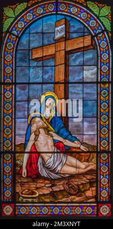 DOMODOSSOLA, ITALIEN - 19. JULI 2022: Die Pieta auf dem Buntglas in der Kirche Chiesa dei Santi Gervasio e Protasio von Luigi Fontana ab 19. Cent. Stockfoto