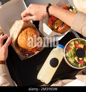 Amerikanische Fast-Food-Spezialitäten. Mittagessen auf einem Tablett, Burger mit Fleisch, Hot Dog. Fast Food auf der Straße, Blick von oben Stockfoto