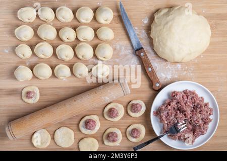 Der Prozess der Herstellung hausgemachter Knödel. Hackfleisch auf dem Teig. Russisches Essen Stockfoto