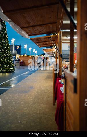 Spanischer Weihnachtsmarkt an einem regnerischen Tag. Verschiedene Verkäufer mit weihnachtsdekoration und Lichtern. Stockfoto