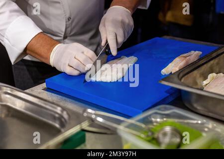 Der Koch hackt die Seezunge. Den Fisch mit einem Messer schneiden. Stockfoto