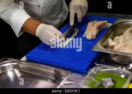 Der Koch hackt die Seezunge. Den Fisch mit einem Messer schneiden. Stockfoto