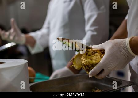 Die Hand des Kochs hackt Sellerie in einem Topf. Kochen Sie Gemüse zerkleinern Stockfoto