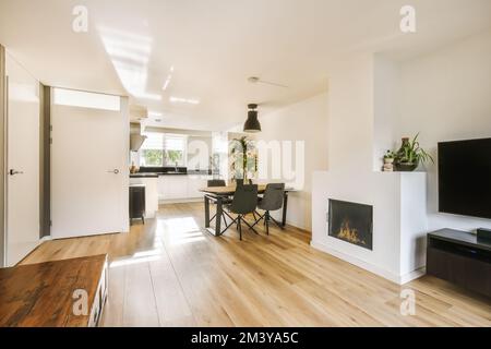 Ein Wohnzimmer mit Holzfußboden und ein Flachbildfernseher an der Wand vor dem Kamin Stockfoto