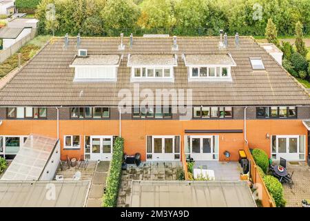 Ein Haus in den niederlanden aus der Vogelperspektive mit Sonnenkollektoren auf dem Dach und einigen grünen Bäumen dahinter Stockfoto