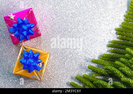 Weihnachtsdekorationen mit Kugeln, Geschenken und Piniennadeln mit Platz für Text und glänzendem Hintergrund Stockfoto