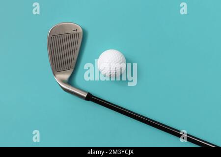 Golfschläger und Golfball isoliert auf helltürkisblauem Hintergrund. Sportbegriff. Platz für Text. Stockfoto