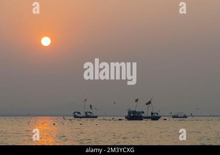 Sonnenaufgang über Booten mit Pilgern in Sangam, dem Zusammenfluss der heiligen Flüsse Ganges, Yamuna und Saraswati Stockfoto